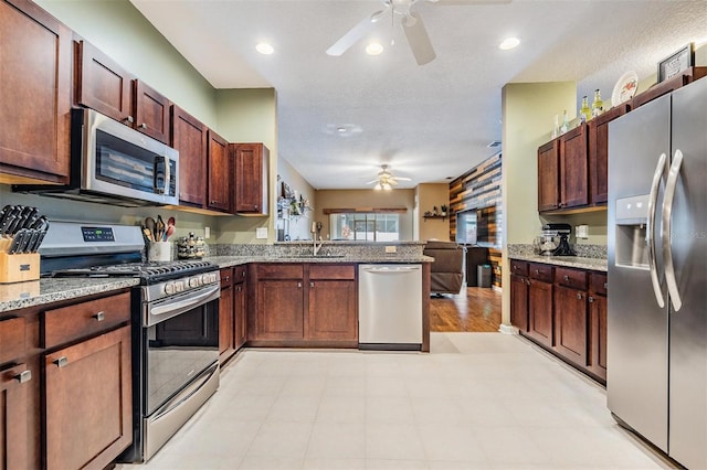 19351 Haskell Pl, Land O Lakes, FL 34638 - kitchen with stainless steel appliances, ceiling fan, a peninsula, light stone counters, and open floor plan