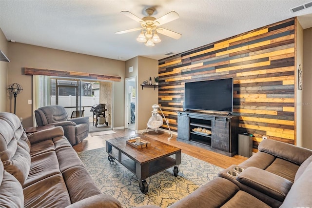 19351 Haskell Pl, Land O Lakes, FL 34638 - living area with a ceiling fan, wood walls, an accent wall, wood finished floors, and a fireplace