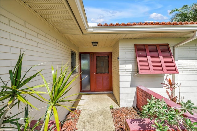 557 Crystal Dr, Madeira Beach, FL 33708 - entrance to property featuring brick siding, a tiled roof, and a porch