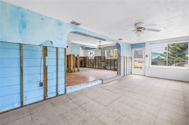 557 Crystal Dr, Madeira Beach, FL 33708 - unfurnished living room featuring ceiling fan, arched walkways, and a textured ceiling