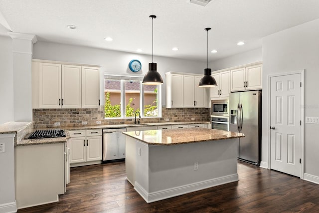 1304 Lorea Ln, Brandon, FL 33511 - kitchen featuring stainless steel appliances, dark wood finished floors, backsplash, light stone counters, and a center island