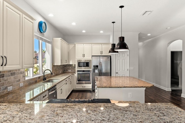 1304 Lorea Ln, Brandon, FL 33511 - kitchen featuring appliances with stainless steel finishes, arched walkways, dark wood-style floors, light stone countertops, and a kitchen island