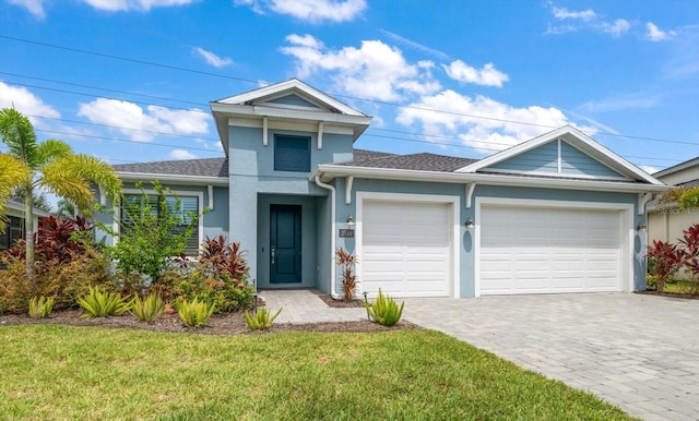 2516 Cobalt Shores Ln, Clearwater, FL 33761 - view of front facade featuring a garage, stucco siding, a front yard, decorative driveway, and a shingled roof