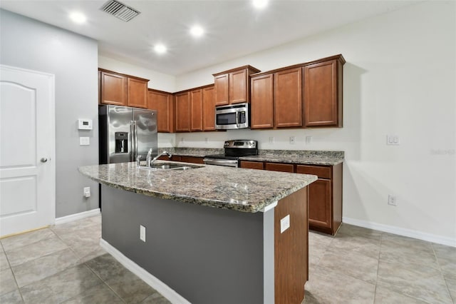 10409 Orchid Mist Ct, Riverview, FL 33578 - kitchen featuring appliances with stainless steel finishes, stone counters, a kitchen island with sink, brown cabinetry, and recessed lighting