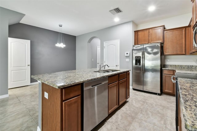 10409 Orchid Mist Ct, Riverview, FL 33578 - kitchen featuring stainless steel appliances, arched walkways, a center island with sink, light stone counters, and pendant lighting