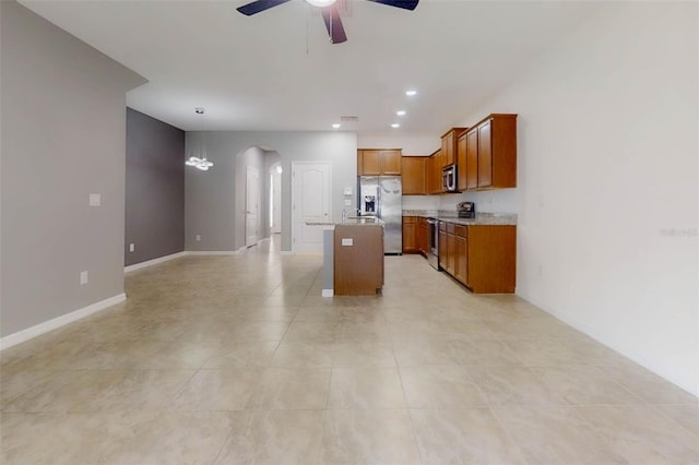 10409 Orchid Mist Ct, Riverview, FL 33578 - kitchen with stainless steel appliances, arched walkways, a ceiling fan, brown cabinetry, and open floor plan