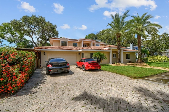 1020 Charles St, Clearwater, FL 33755 - mediterranean / spanish-style home featuring decorative driveway, an attached garage, stucco siding, a front lawn, and a tiled roof