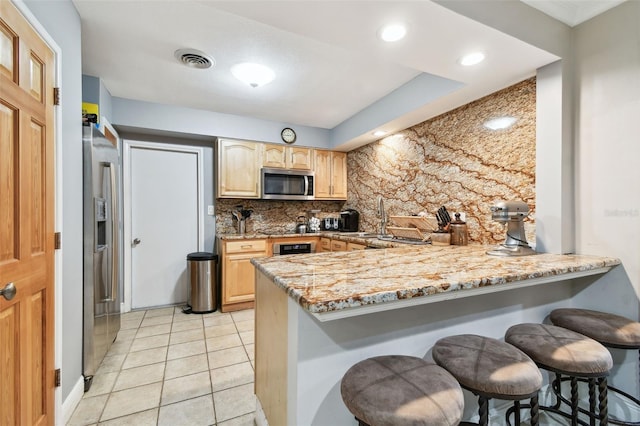 1020 Charles St, Clearwater, FL 33755 - kitchen with light brown cabinets, a peninsula, decorative backsplash, stainless steel appliances, and recessed lighting