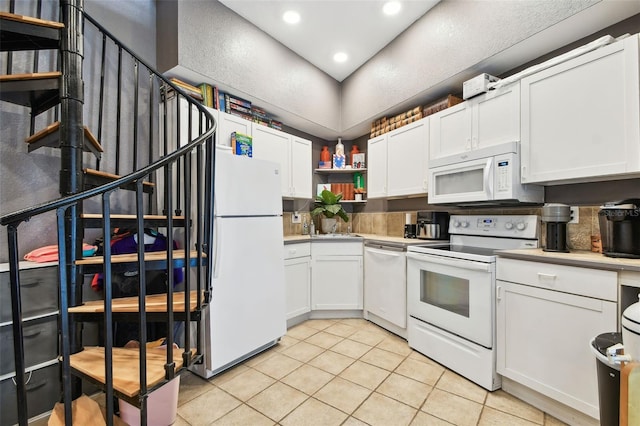 1020 Charles St, Clearwater, FL 33755 - kitchen with white appliances, light tile patterned floors, white cabinets, light countertops, and recessed lighting