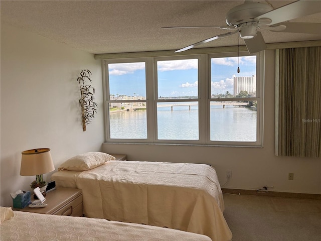 7401 Bay Island Dr S Unit 338, South Pasadena, FL 33707 - bedroom featuring a water view, multiple windows, carpet flooring, ceiling fan, and a textured ceiling
