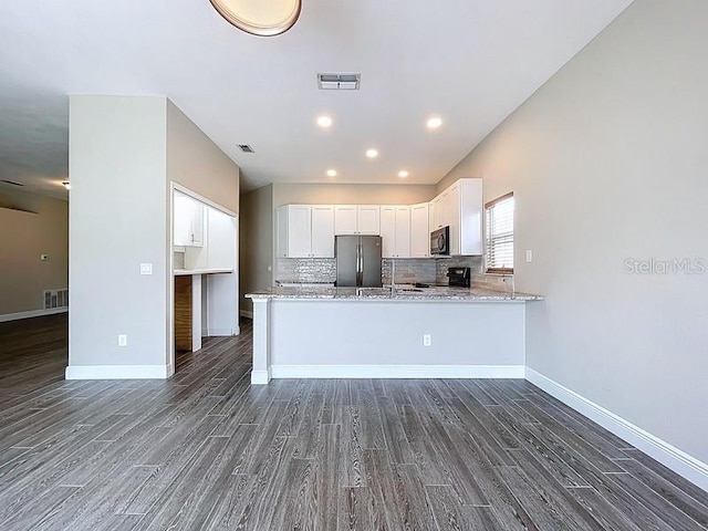 2049 Darlington Oak Dr, Seffner, FL 33584 - kitchen with stainless steel appliances, dark wood-style flooring, white cabinets, light stone counters, and a peninsula