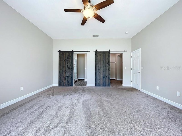 2049 Darlington Oak Dr, Seffner, FL 33584 - unfurnished bedroom with a barn door, carpet floors, ceiling fan, and a walk in closet