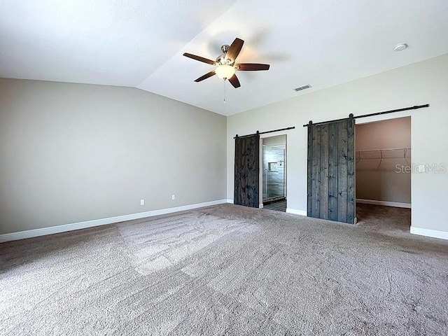 2049 Darlington Oak Dr, Seffner, FL 33584 - unfurnished bedroom featuring a barn door, a spacious closet, lofted ceiling, ceiling fan, and carpet flooring