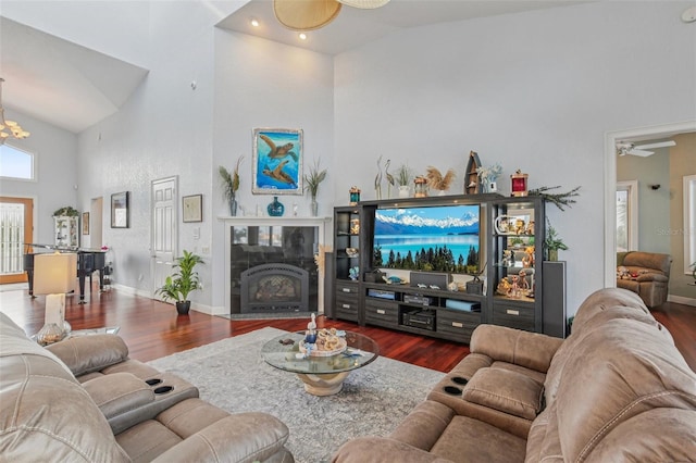 5521 Windward Way, New Port Richey, FL 34652 - living area featuring high vaulted ceiling, wood finished floors, ceiling fan, a tiled fireplace, and a chandelier