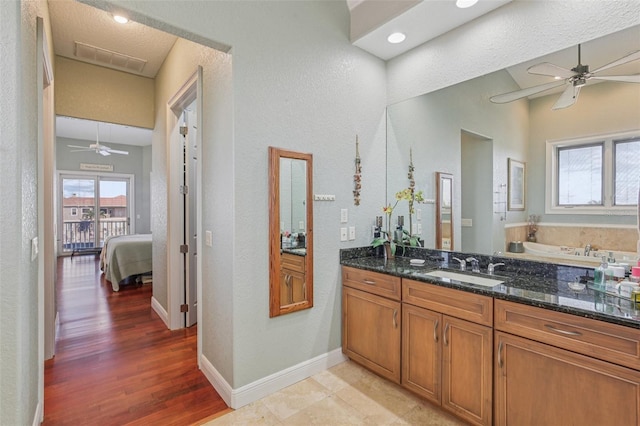 5521 Windward Way, New Port Richey, FL 34652 - ensuite bathroom featuring ceiling fan, vanity, a textured wall, wood finished floors, and a bath