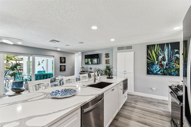 11599 Grove St, Seminole, FL 33772 - kitchen featuring dishwasher, gas stove, a textured ceiling, white cabinets, and light stone counters