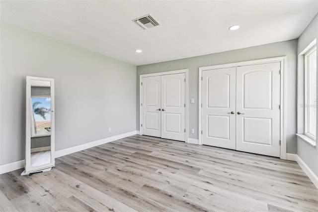 11599 Grove St, Seminole, FL 33772 - unfurnished bedroom with multiple closets, light wood-type flooring, and recessed lighting