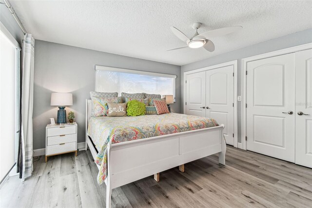 11599 Grove St, Seminole, FL 33772 - bedroom featuring light wood-style flooring, two closets, a ceiling fan, and a textured ceiling