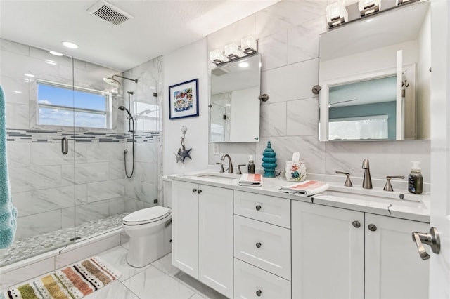 11599 Grove St, Seminole, FL 33772 - bathroom with a shower stall, marble finish floors, double vanity, tile walls, and backsplash