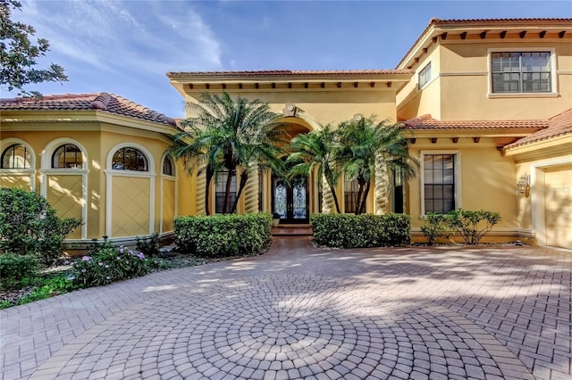 10504 Sabella Dr, Trinity, FL 34655 - mediterranean / spanish-style home featuring stucco siding, french doors, decorative driveway, and a tile roof