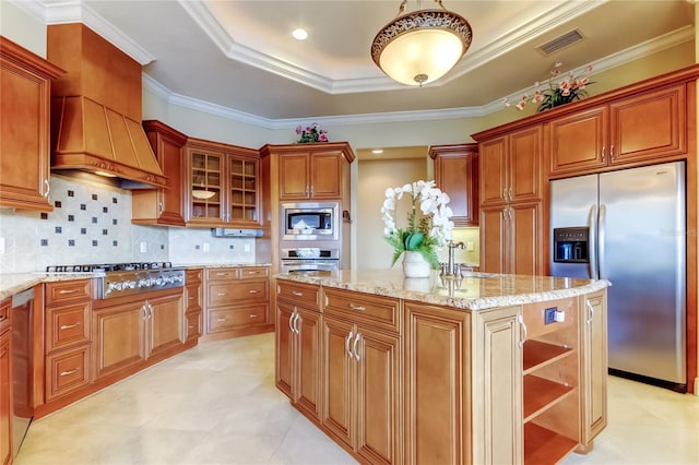 10504 Sabella Dr, Trinity, FL 34655 - kitchen featuring appliances with stainless steel finishes, a raised ceiling, a kitchen island, crown molding, and light stone countertops