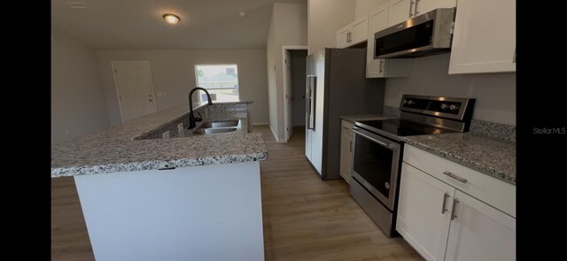 4251 E Walker St, Inverness, FL 34453 - kitchen with stainless steel appliances, a kitchen island with sink, white cabinets, light wood-style floors, and light stone countertops