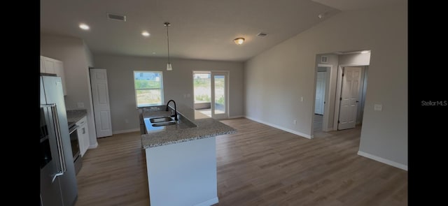 4251 E Walker St, Inverness, FL 34453 - kitchen with white cabinets, an island with sink, stainless steel refrigerator with ice dispenser, lofted ceiling, and light wood-style flooring