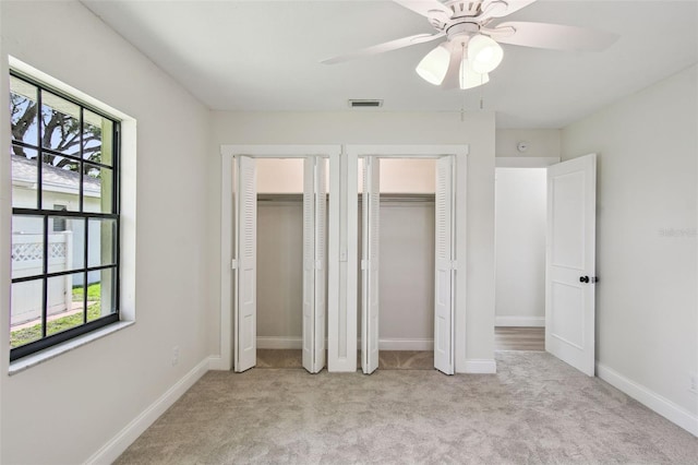 2004 Varner Cir, Winter Haven, FL 33884 - unfurnished bedroom featuring two closets, multiple windows, light carpet, and ceiling fan