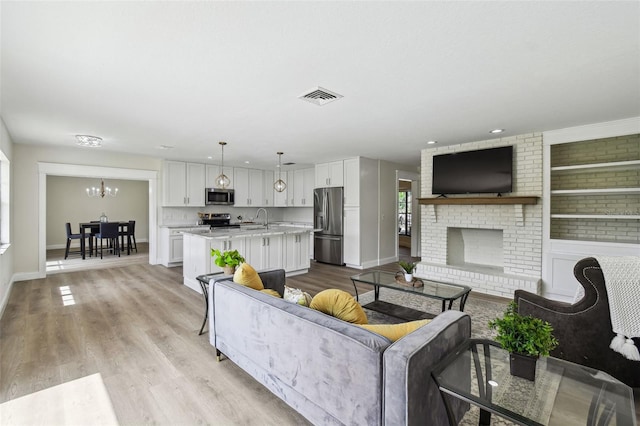 2004 Varner Cir, Winter Haven, FL 33884 - living room featuring a chandelier, light wood-style floors, and a brick fireplace