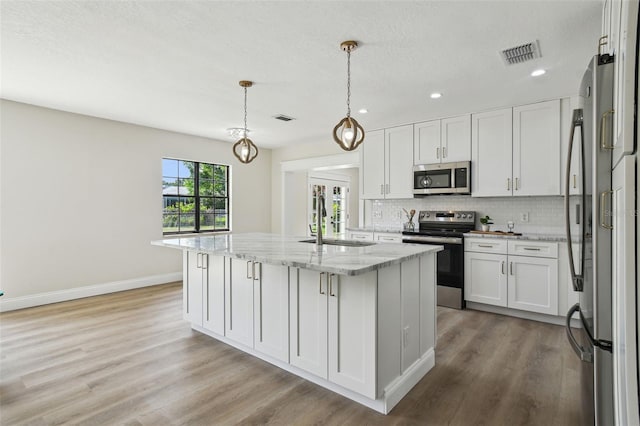 2004 Varner Cir, Winter Haven, FL 33884 - kitchen featuring appliances with stainless steel finishes, light wood-type flooring, white cabinetry, tasteful backsplash, and recessed lighting