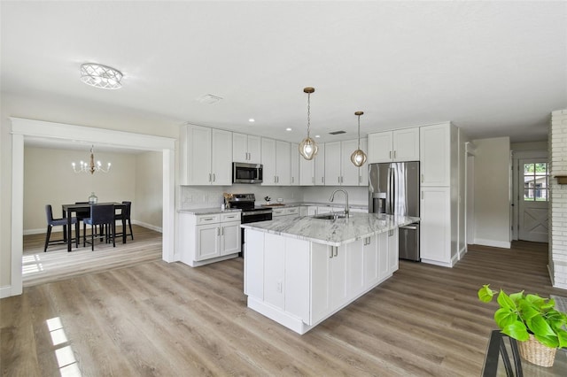 2004 Varner Cir, Winter Haven, FL 33884 - kitchen with appliances with stainless steel finishes, white cabinets, light stone counters, a chandelier, and light wood-style floors