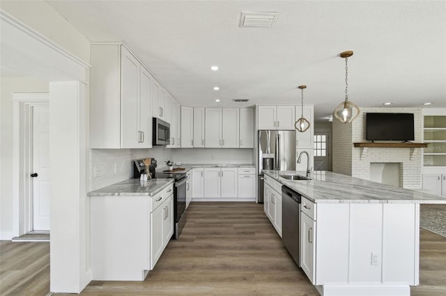 2004 Varner Cir, Winter Haven, FL 33884 - kitchen featuring stainless steel appliances, white cabinets, wood finished floors, light stone countertops, and recessed lighting