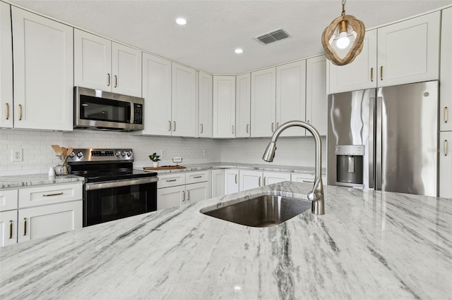 2004 Varner Cir, Winter Haven, FL 33884 - kitchen featuring appliances with stainless steel finishes, white cabinets, backsplash, light stone counters, and recessed lighting
