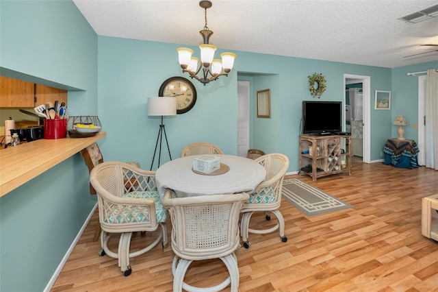 5265 E Bay Dr Unit 313, Clearwater, FL 33764 - dining room with light wood finished floors, a chandelier, and a textured ceiling