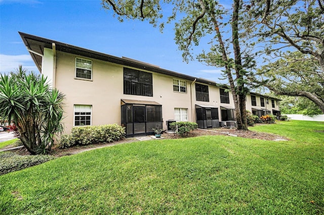 5265 E Bay Dr Unit 313, Clearwater, FL 33764 - back of property with stucco siding, a yard, and a sunroom