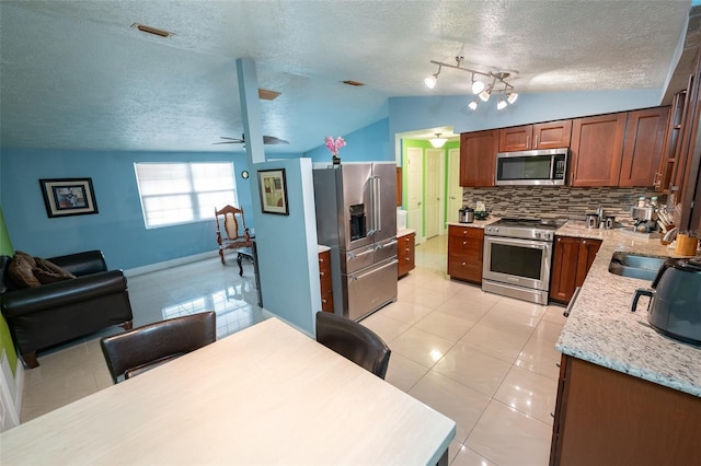 4239 Cardoon Dr, New Port Richey, FL 34653 - kitchen with high end appliances, vaulted ceiling, a textured ceiling, decorative backsplash, and light tile patterned floors