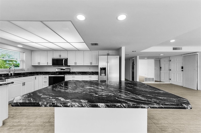 3021 Countryside Blvd Unit 28A, Clearwater, FL 33761 - kitchen with stainless steel appliances, recessed lighting, dark stone counters, white cabinets, and a center island
