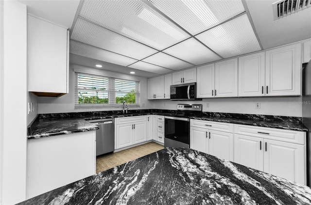 3021 Countryside Blvd Unit 28A, Clearwater, FL 33761 - kitchen with stainless steel appliances, light wood-type flooring, white cabinetry, dark stone counters, and recessed lighting