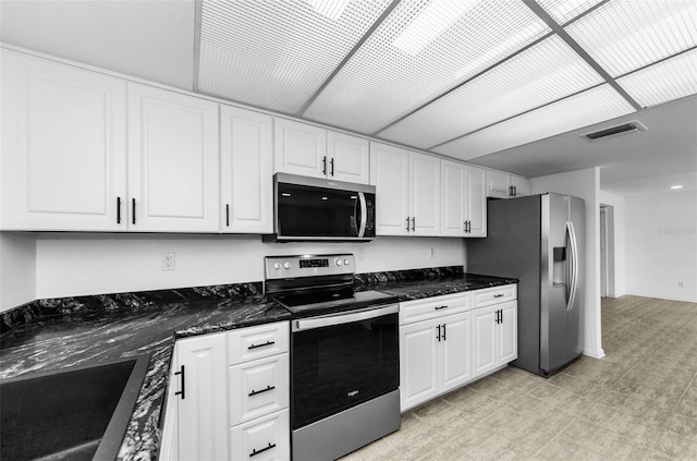 3021 Countryside Blvd Unit 28A, Clearwater, FL 33761 - kitchen featuring appliances with stainless steel finishes, white cabinetry, light flooring, and dark stone counters