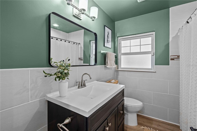 327 Sunny Ln, Belleair, FL 33756 - bathroom featuring tile walls, vanity, wood finished floors, a shower with shower curtain, and a wainscoted wall