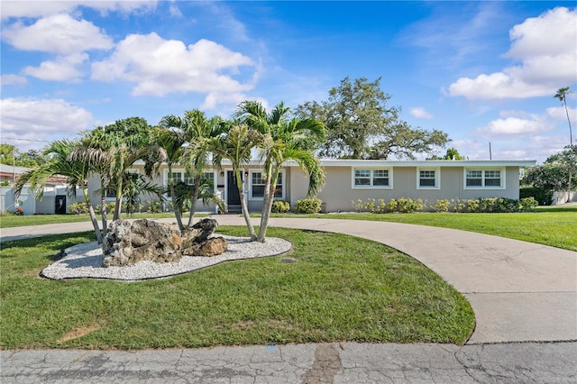 327 Sunny Ln, Belleair, FL 33756 - ranch-style home with curved driveway, a front yard, and stucco siding