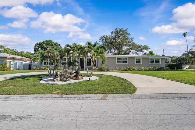 327 Sunny Ln, Belleair, FL 33756 - ranch-style house with curved driveway, a front lawn, and stucco siding