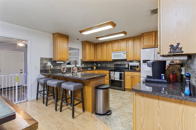 70 Arthur Ln, Winter Haven, FL 33880 - kitchen with white appliances, a peninsula, backsplash, ceiling fan, and dark stone countertops