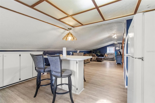 70 Arthur Ln, Winter Haven, FL 33880 - kitchen with freestanding refrigerator, light wood-type flooring, lofted ceiling, white cabinetry, and a kitchen breakfast bar
