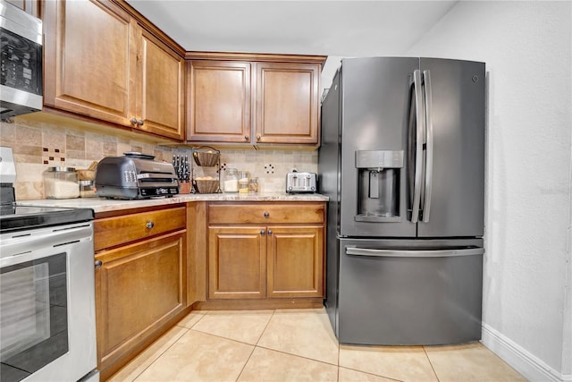 12402 84th Way, Largo, FL 33773 - kitchen featuring appliances with stainless steel finishes, tasteful backsplash, brown cabinets, light tile patterned flooring, and light stone counters