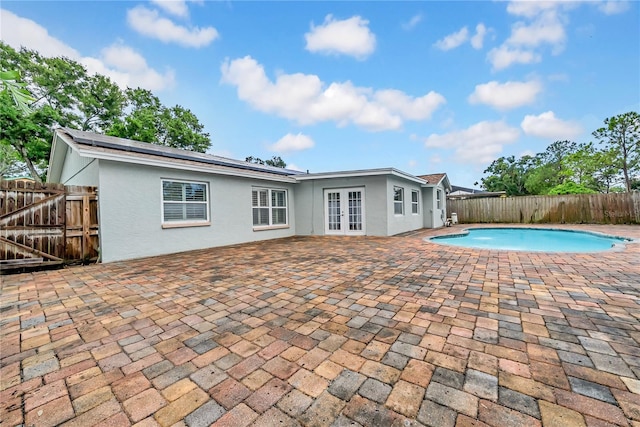 12402 84th Way, Largo, FL 33773 - back of property featuring french doors, stucco siding, a fenced backyard, a patio, and roof mounted solar panels