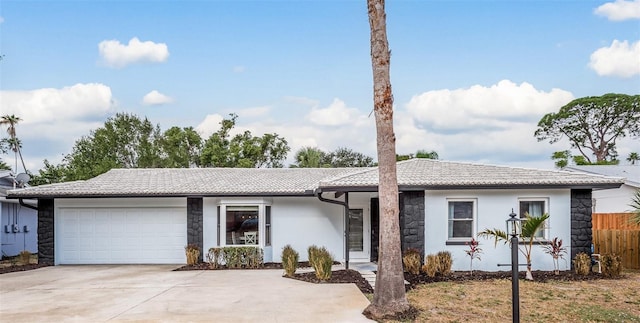 1762 Bayshore Blvd, Dunedin, FL 34698 - ranch-style home featuring stone siding, driveway, an attached garage, a tile roof, and stucco siding