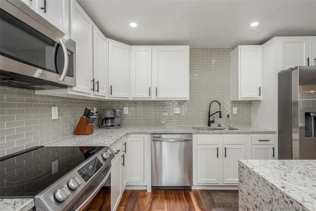 1762 Bayshore Blvd, Dunedin, FL 34698 - kitchen with stainless steel appliances, decorative backsplash, light stone counters, white cabinets, and recessed lighting