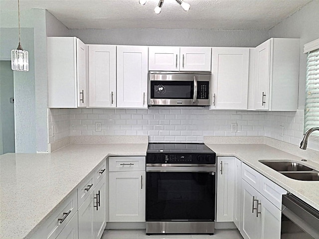 450 82nd Ave, St Pete Beach, FL 33706 - kitchen with range with electric cooktop, stainless steel microwave, dishwashing machine, white cabinetry, and a textured ceiling