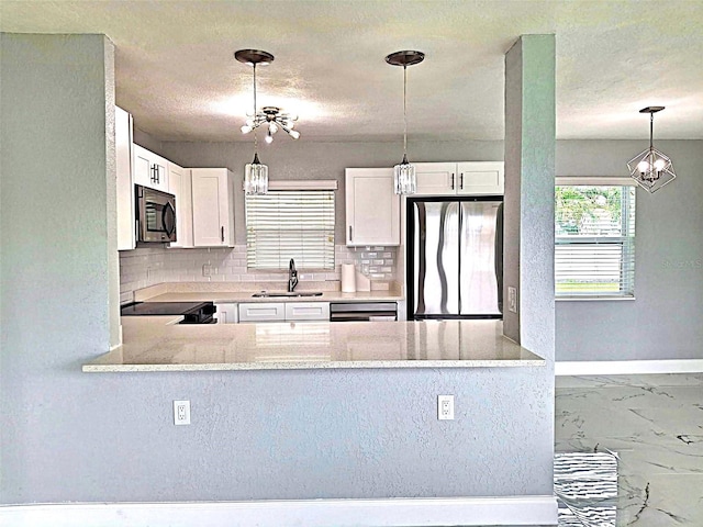 450 82nd Ave, St Pete Beach, FL 33706 - kitchen with stainless steel appliances, a chandelier, tasteful backsplash, hanging light fixtures, and a textured ceiling
